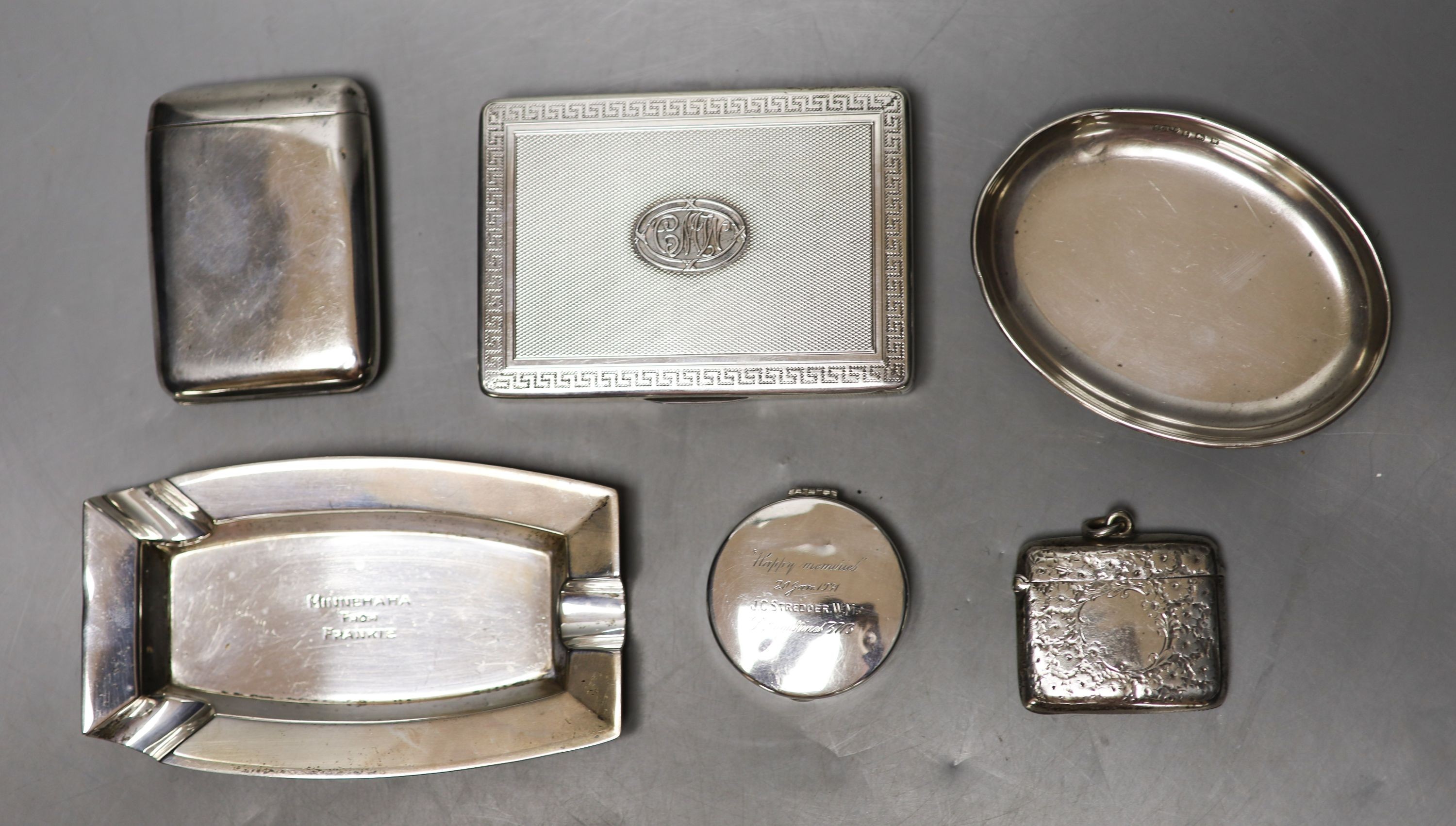 Two silver cigarette cases, largest 10.8cm, a silver vesta case, circular pill box, ashtray and dish.